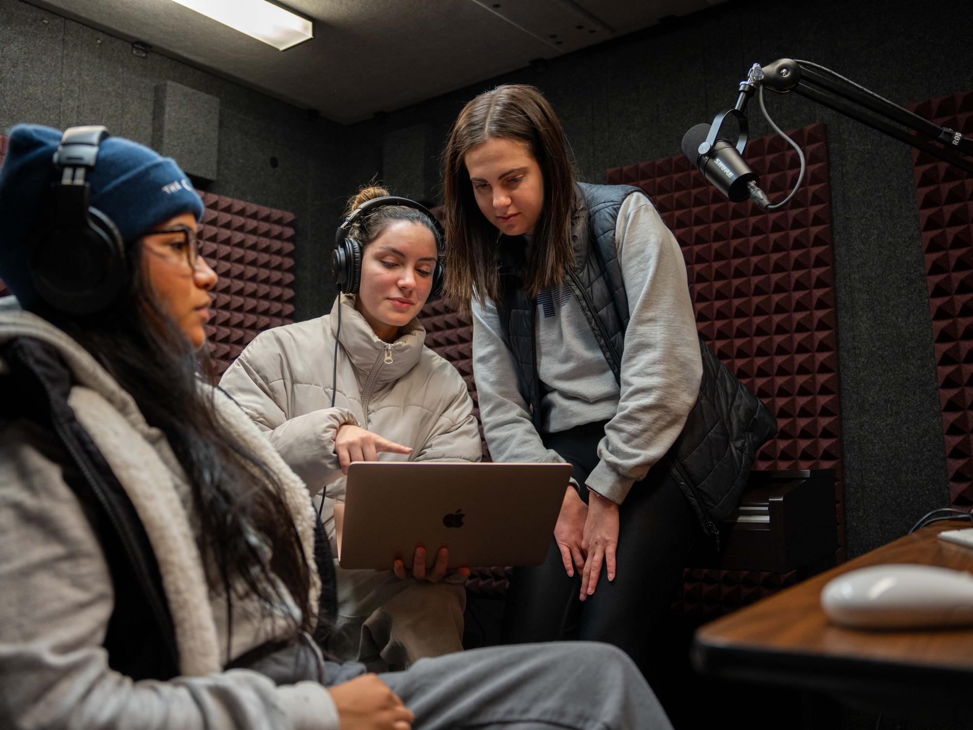 3 female college students sit in a podcasting booth 