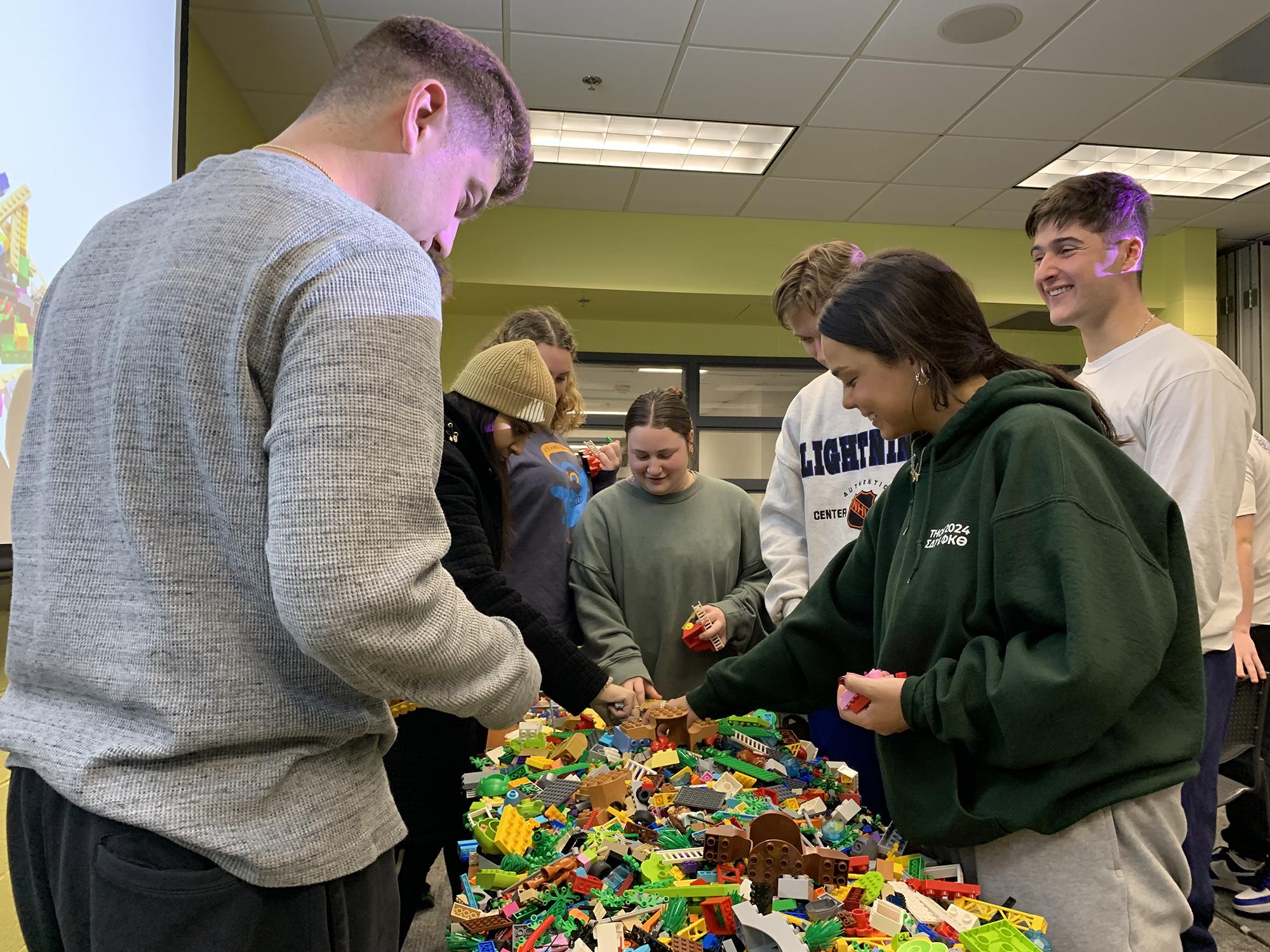 Students standing next to table with Lego blocks