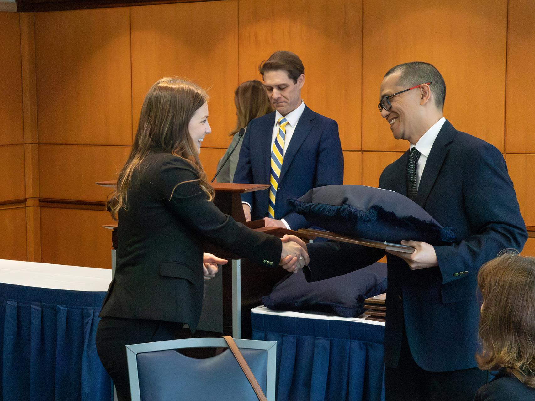 Woolsack inductee Mari Reott shakes hands with Interim Dean Victor Romero at the awards luncheon.