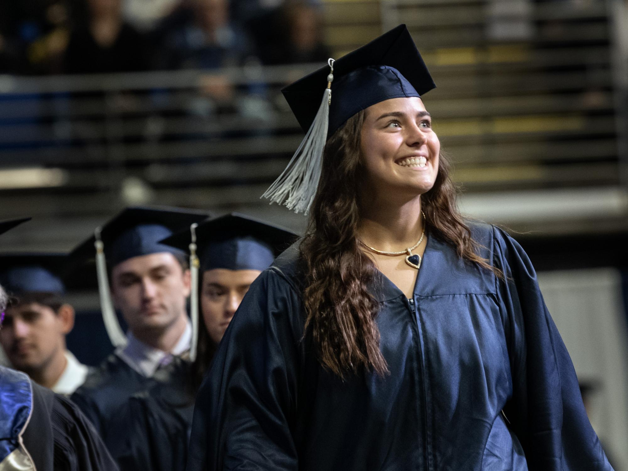 graduate smiles as she walks across stage.