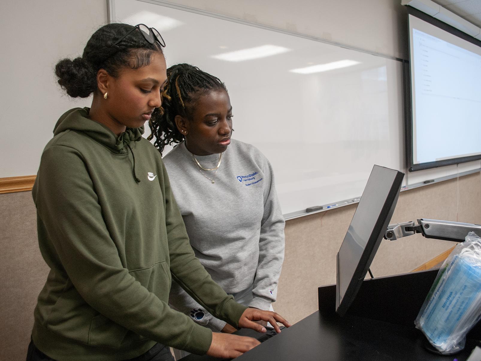 High school student Sarah Gebrezgi and her undergraduate mentor Chelsy-Sippora Funebe look at a computer screen together during an EnvironMentors meeting