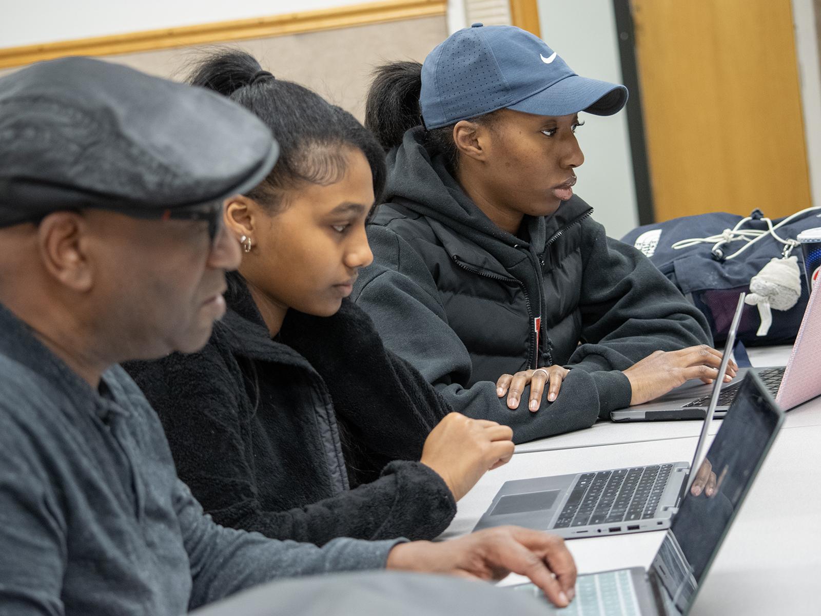 Greg Jenkins, professor of meteorology and atmospheric science at Penn State, high school student Ariam Gebrezgi, and Penn State Harrisburg student Makaylin Valley go over research on their laptops