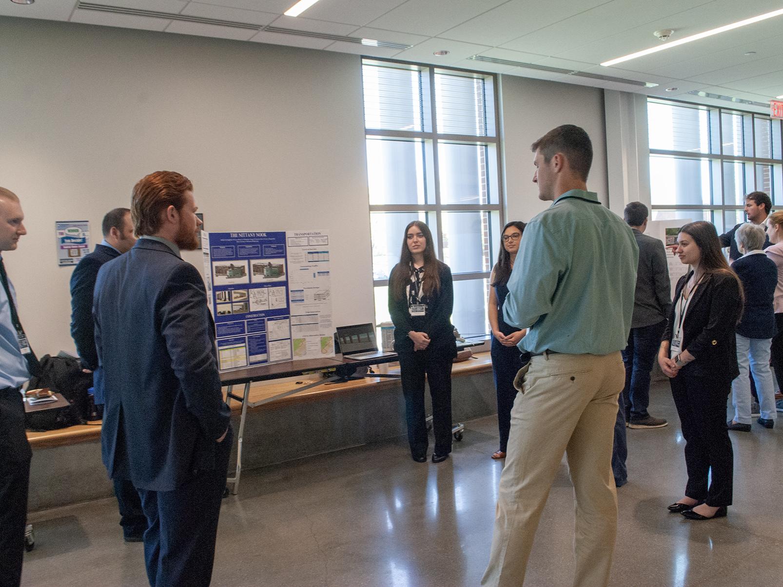 A group of seven people talk around a poster