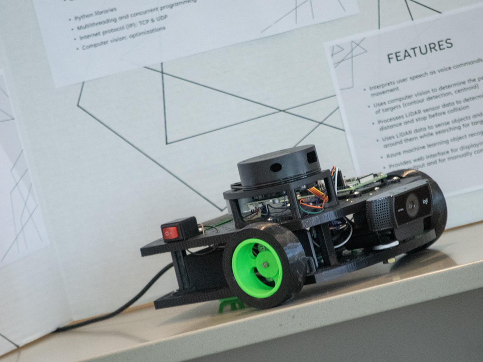 Photo of a voice-controlled robot sitting in front of a research poster