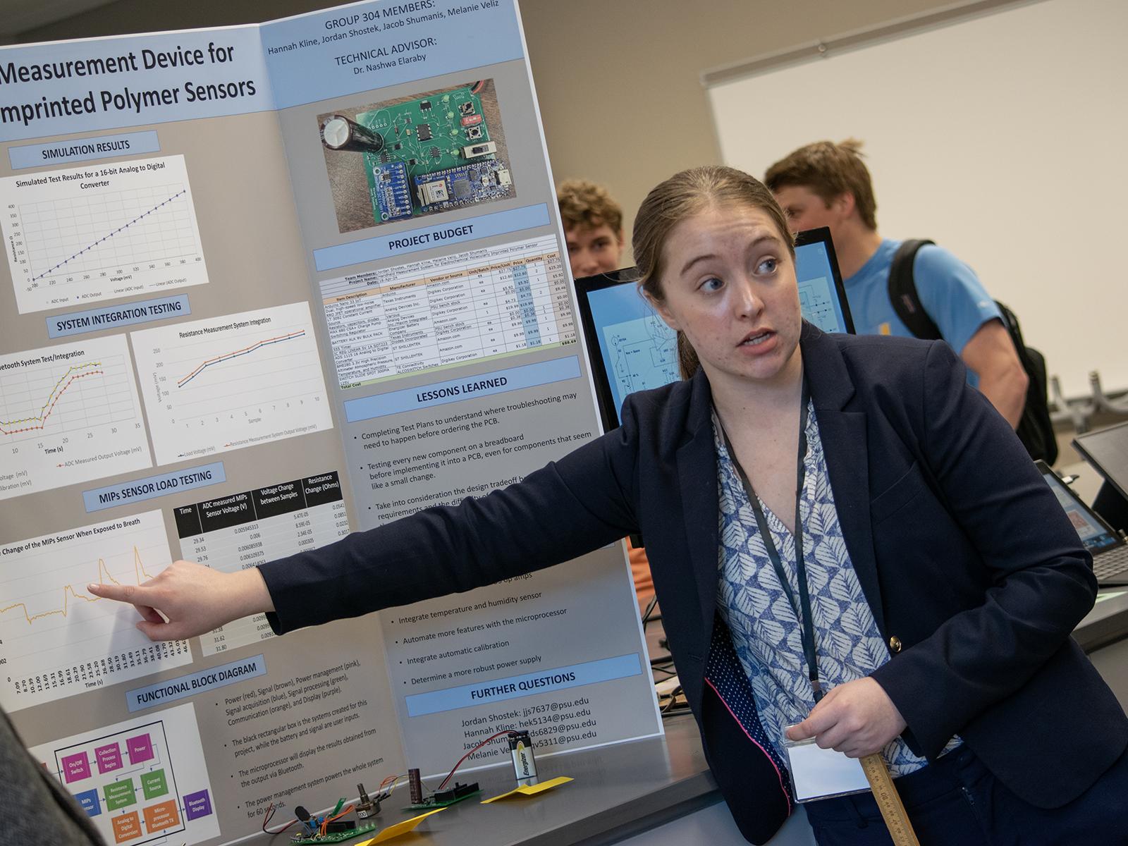 A student points to her poster during the Capstone Design Conference