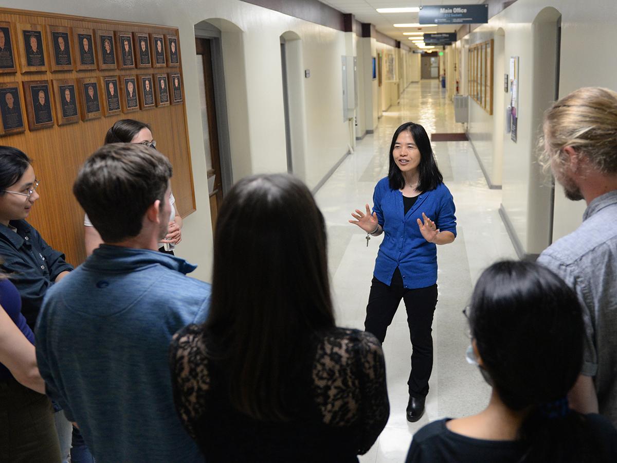 Li Li addresses her research group in a hallway in Hammond Building.