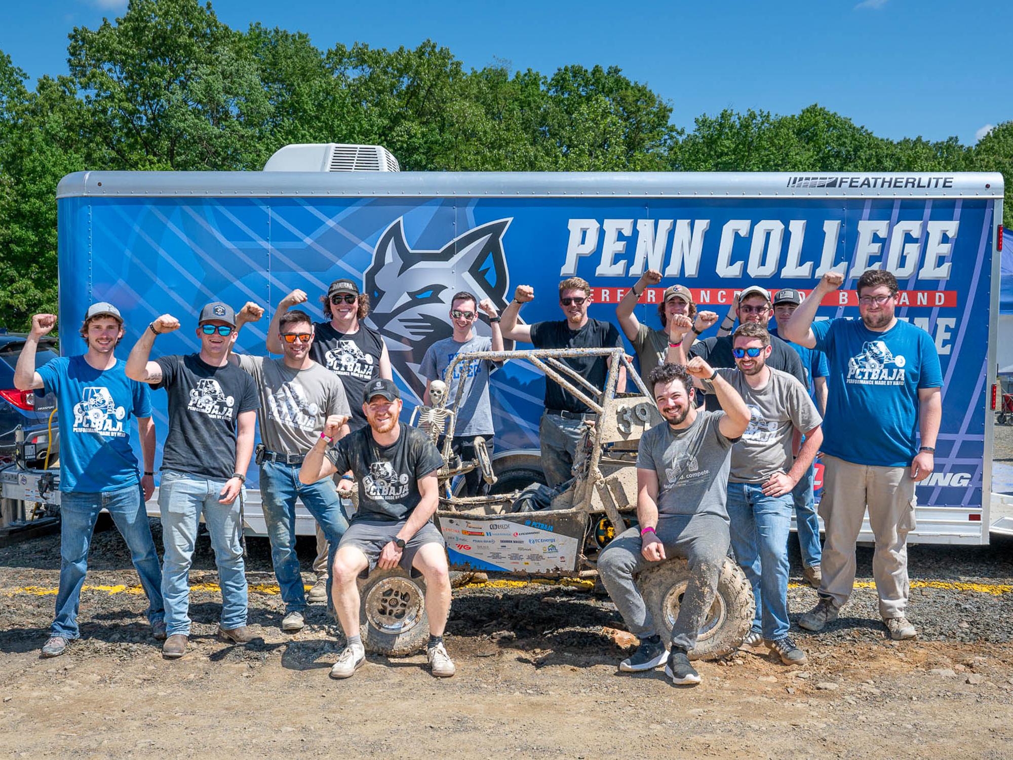 A group of people stand in front of a trailer that says Penn College on it