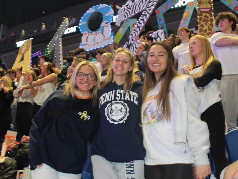 Julie Jenkins (middle) with a friend on either side of her in the stands of the Bryce Jordan Center during THON weekend in February 2024.