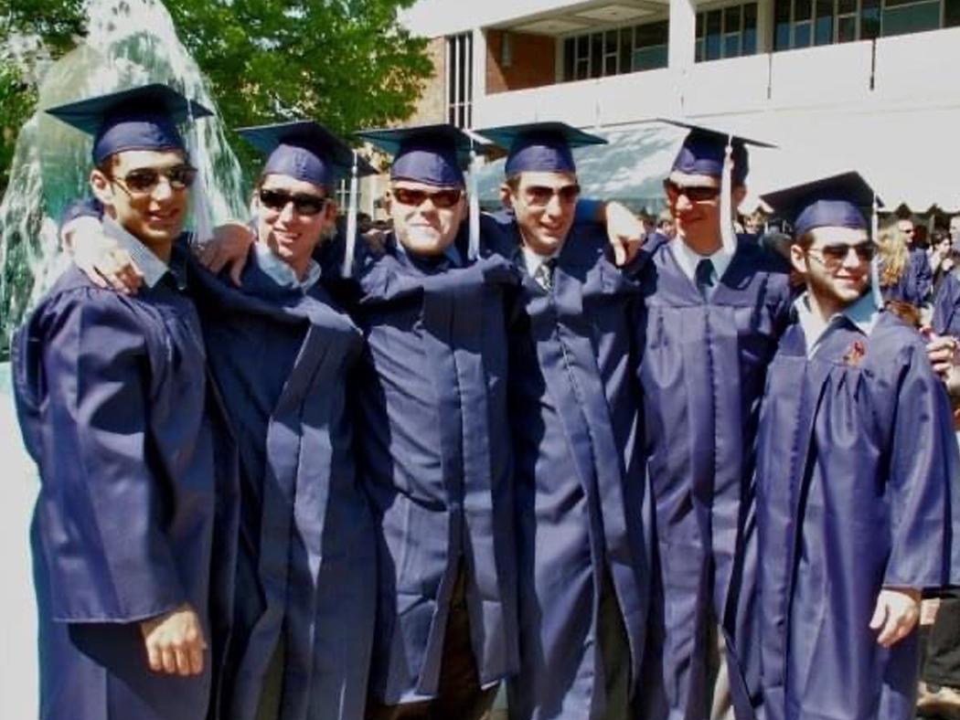 A group of six male students in their blue commencement caps and gowns.