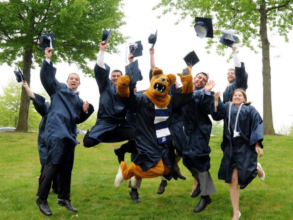 A group of graduates wearing caps and gown jump 