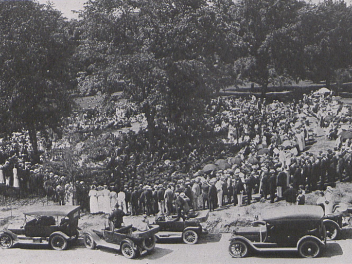 A large group of people stand in a circle around graduates