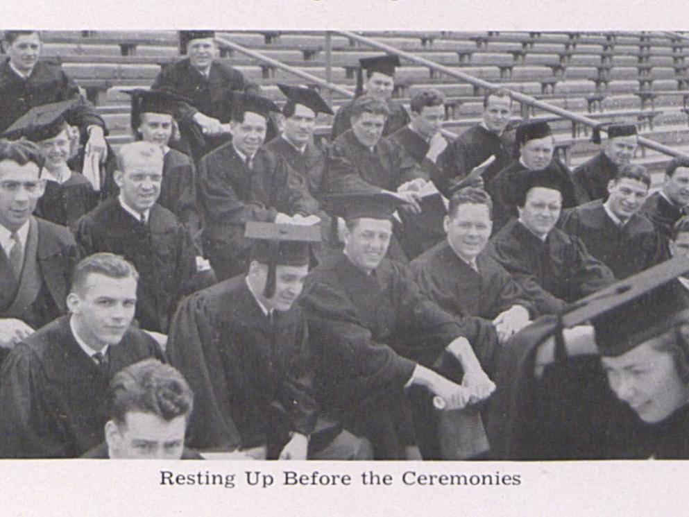 A black and white picture of graduates sitting on bleachers