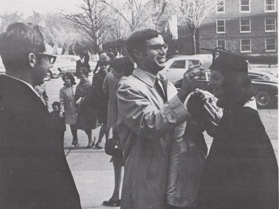 A man helps a graduate with her cap 