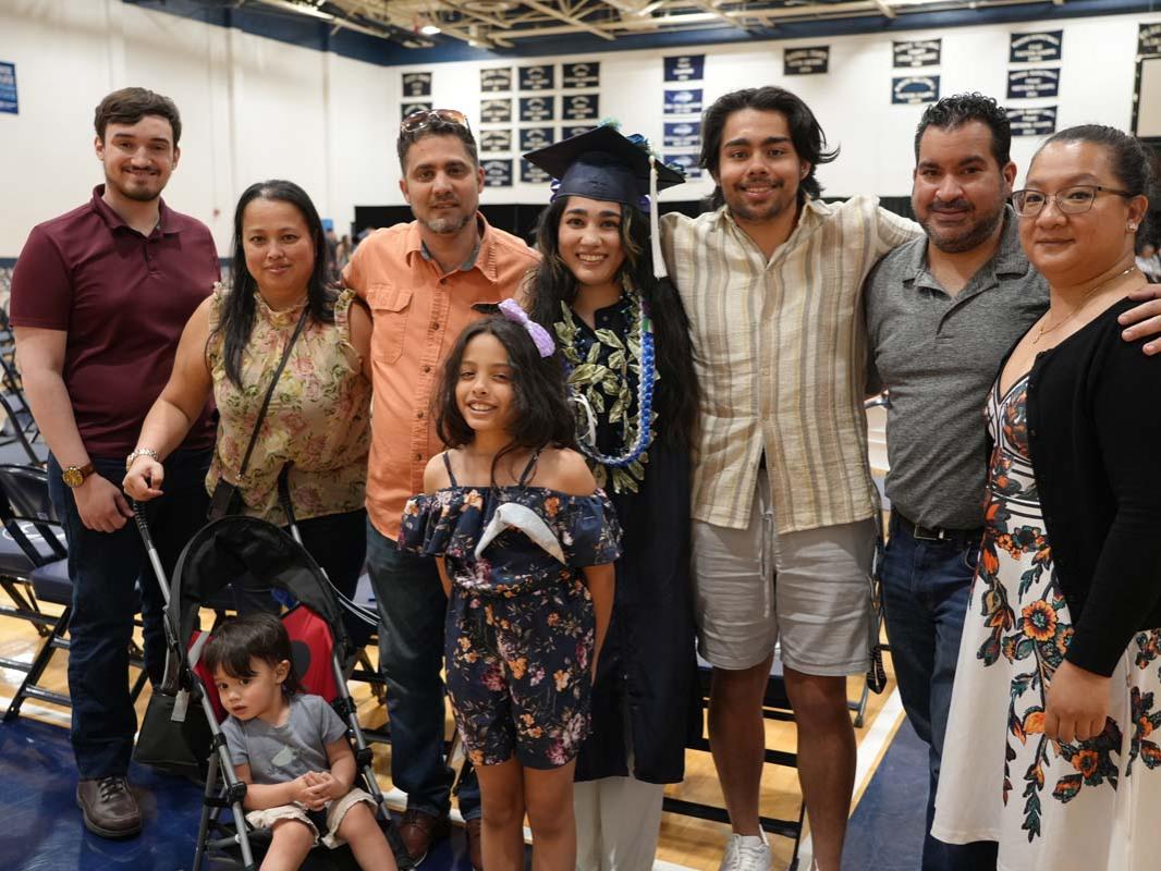 Female graduate posing for a photo surrounded by family.