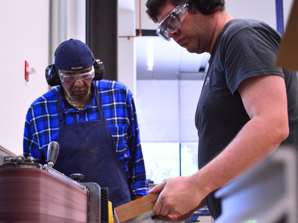 Jose and Edgar work together to use a sander in OriginLabs