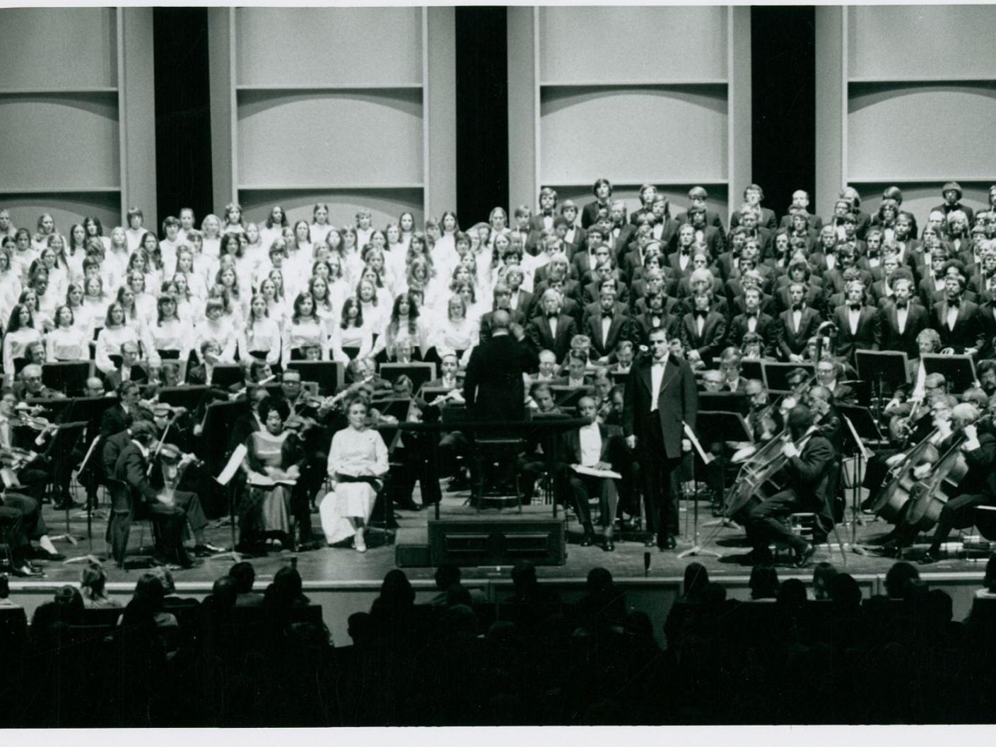 A black and white picture of orchestra and choir members on stage.