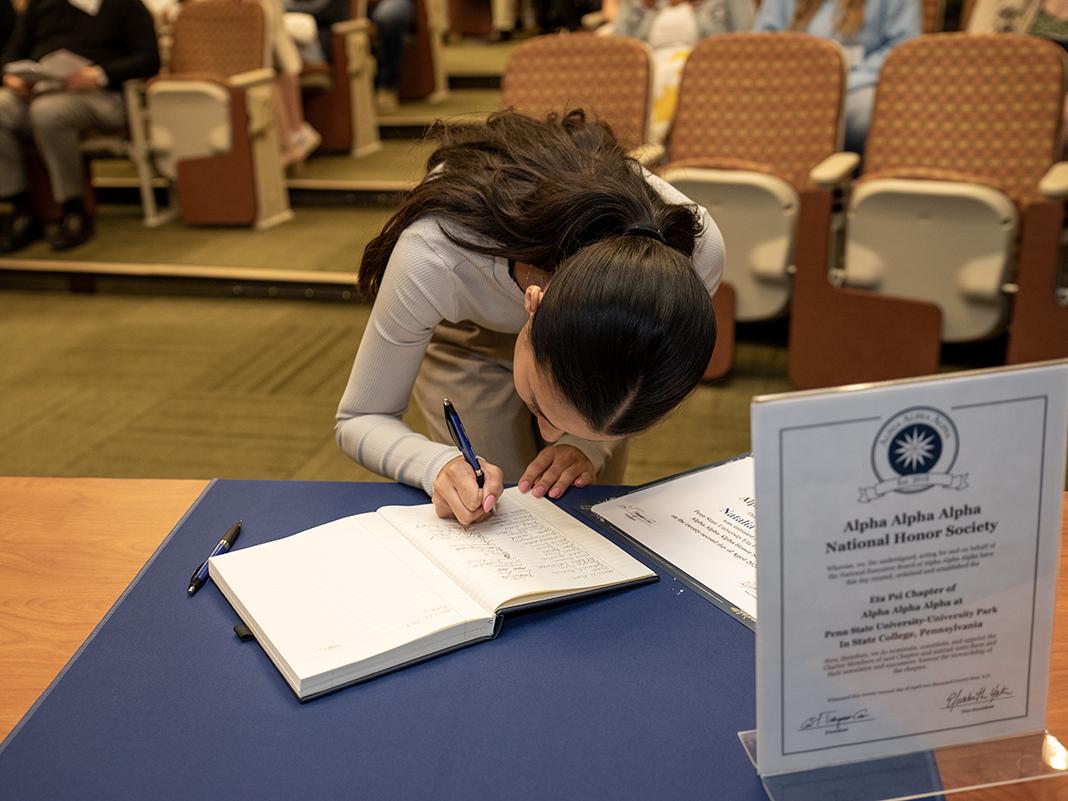 Natalia Guzman signs the Tri-Alpha booklet