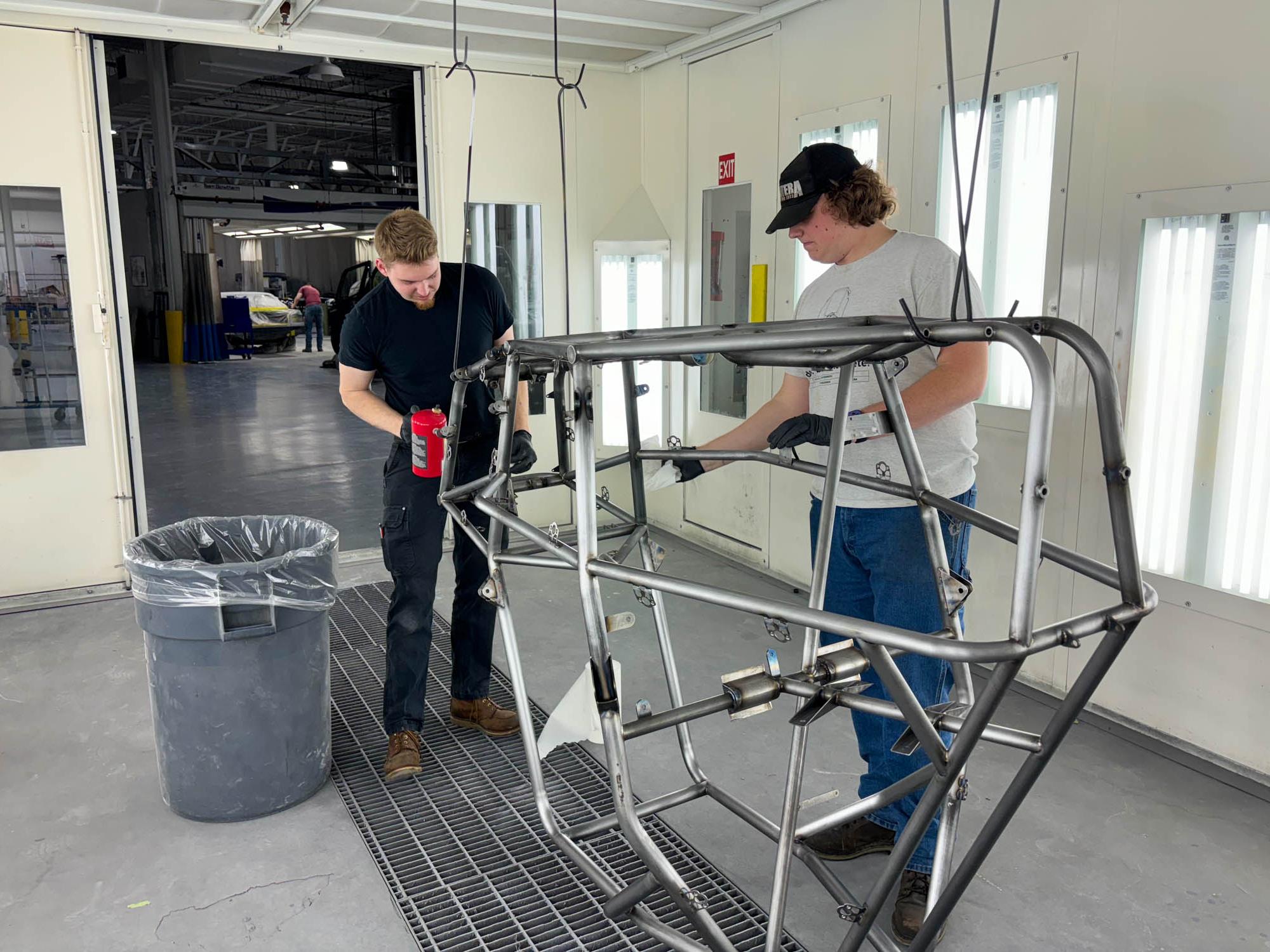 Two students prime the chassis of a car