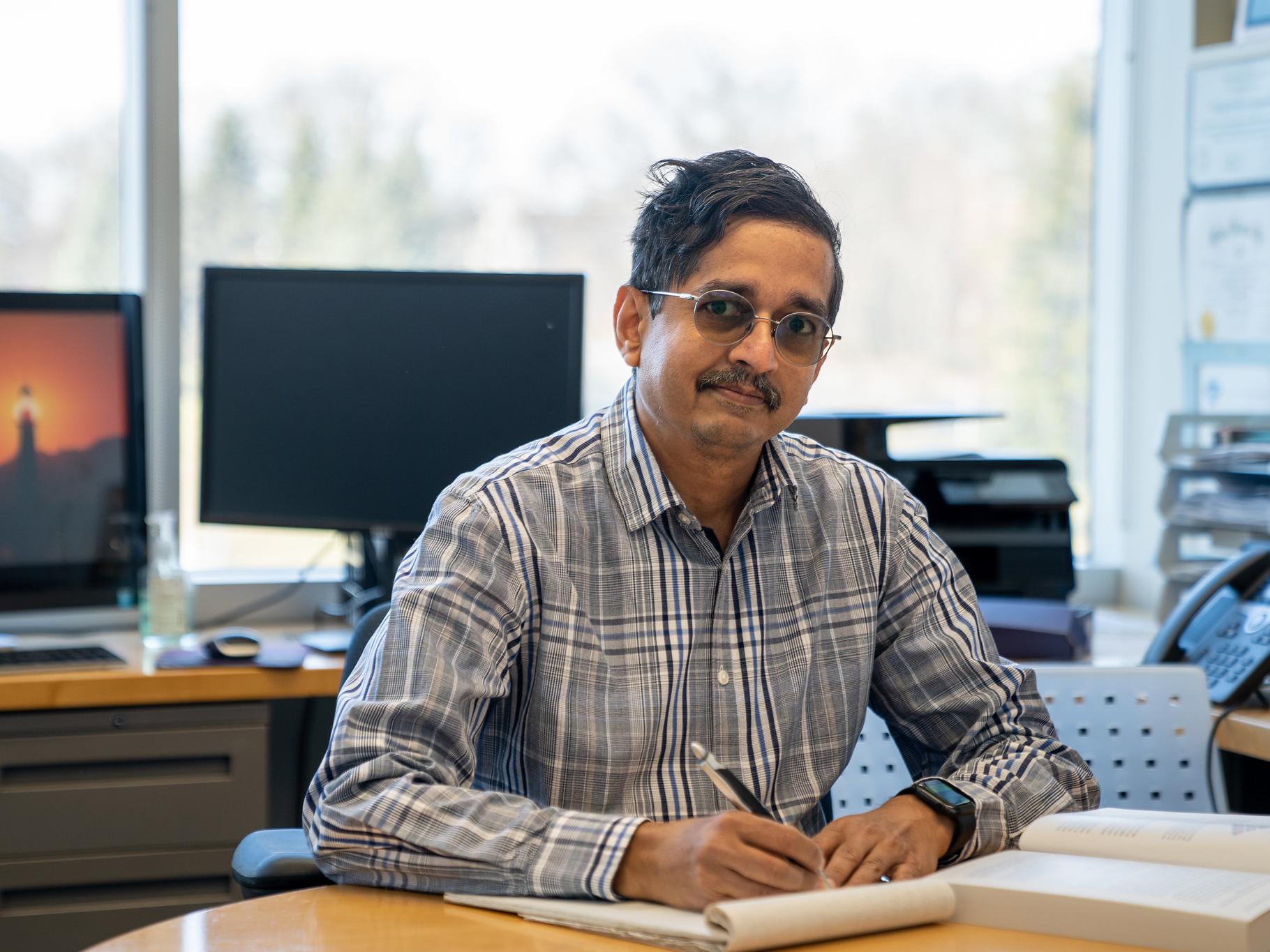 Vijaykrishnan Narayanan smiling and seated at his office desk.