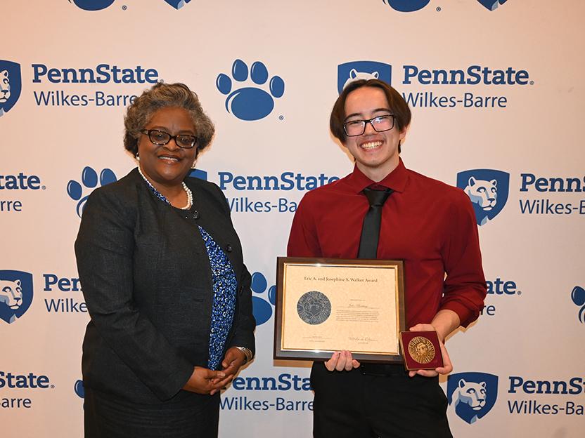 A man at right receiving an award from a woman at left.