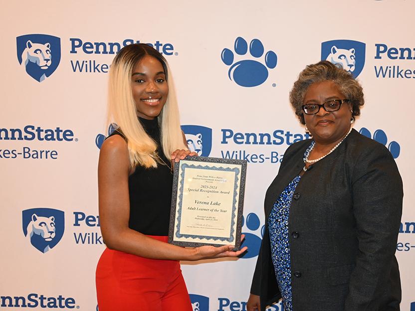 A woman at right presents an award to a woman at left.