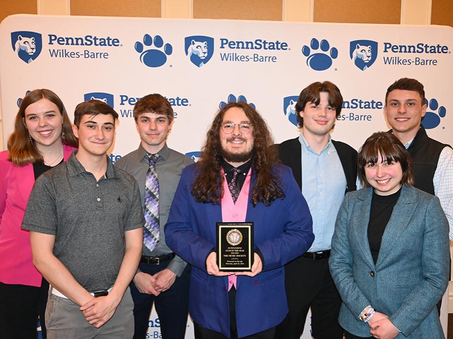 A group of people standing against a backdrop with the Penn State Wilkes-Barre logo.