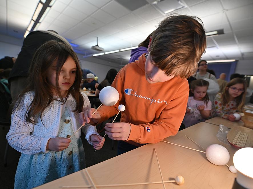 A young girl and boy working on an eclipse craft.