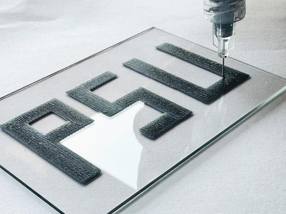 A 3D-printing device is held over a recently printed sample that says PSU.