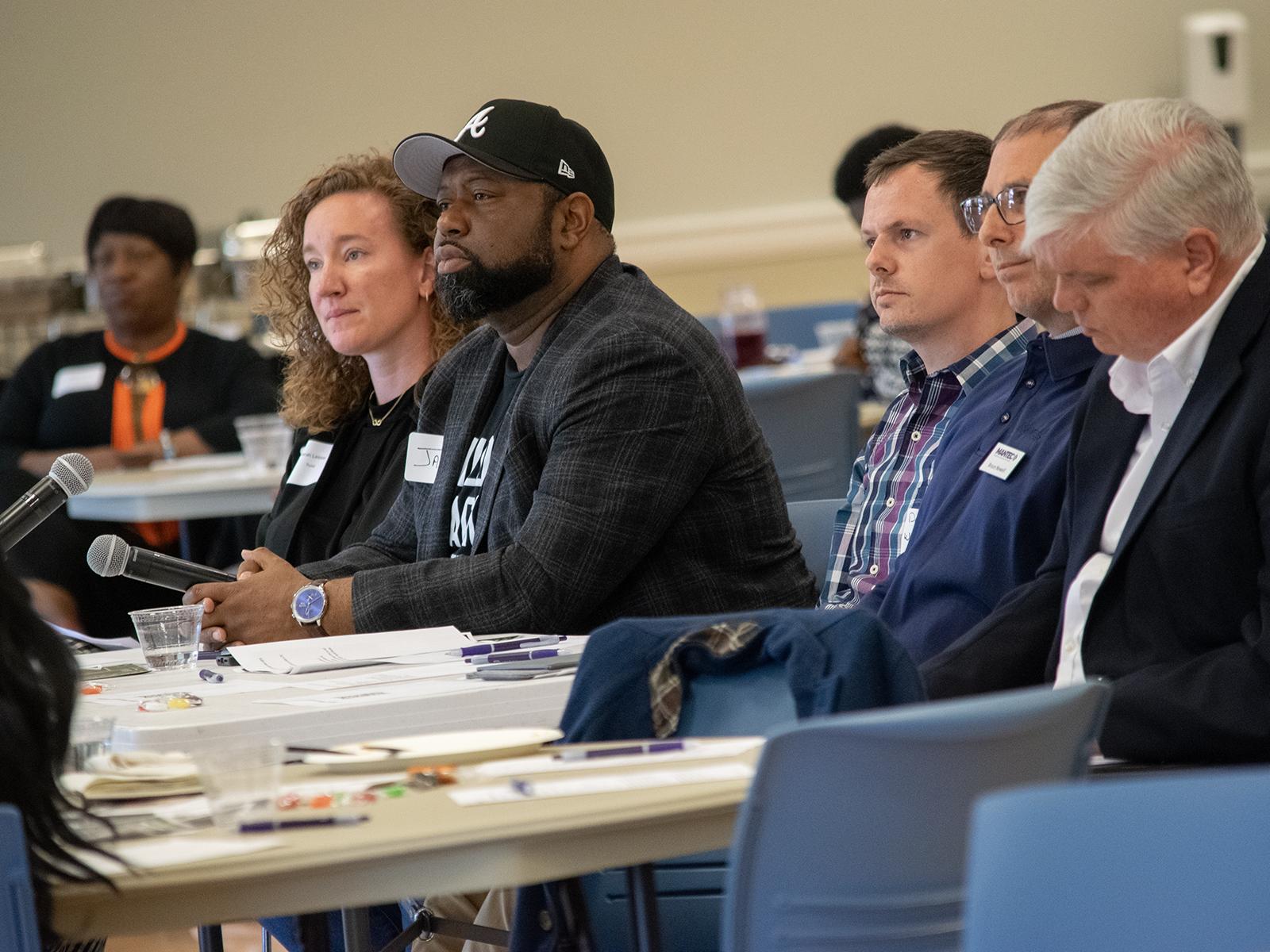 A panel of judges from the business community sit at a table listening to student pitches
