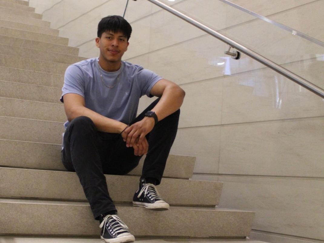 Erick Alonso sits on stairs inside a building at Penn State University Park.