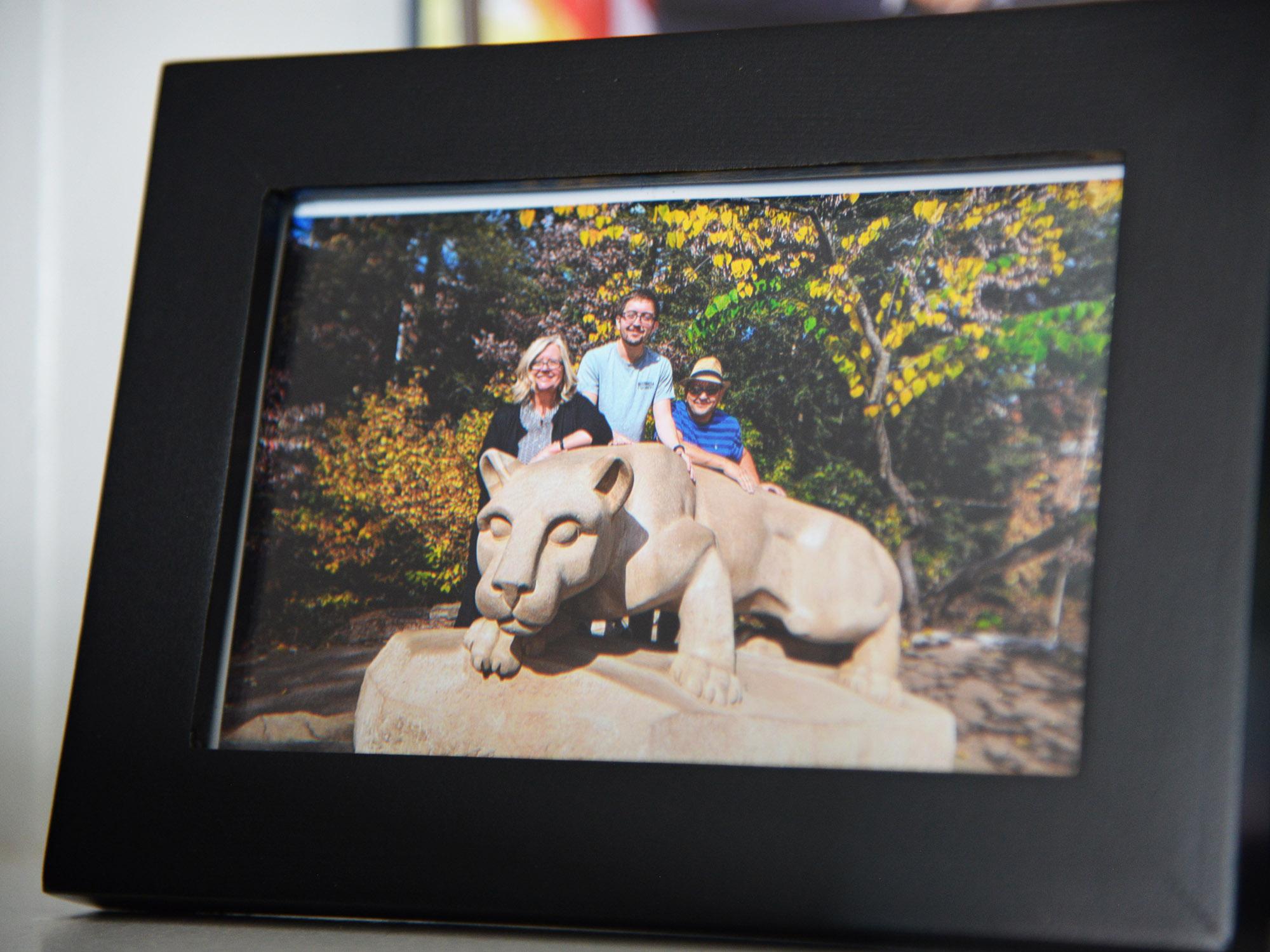 a woman and two men stand behind the nittany lion shrine statue