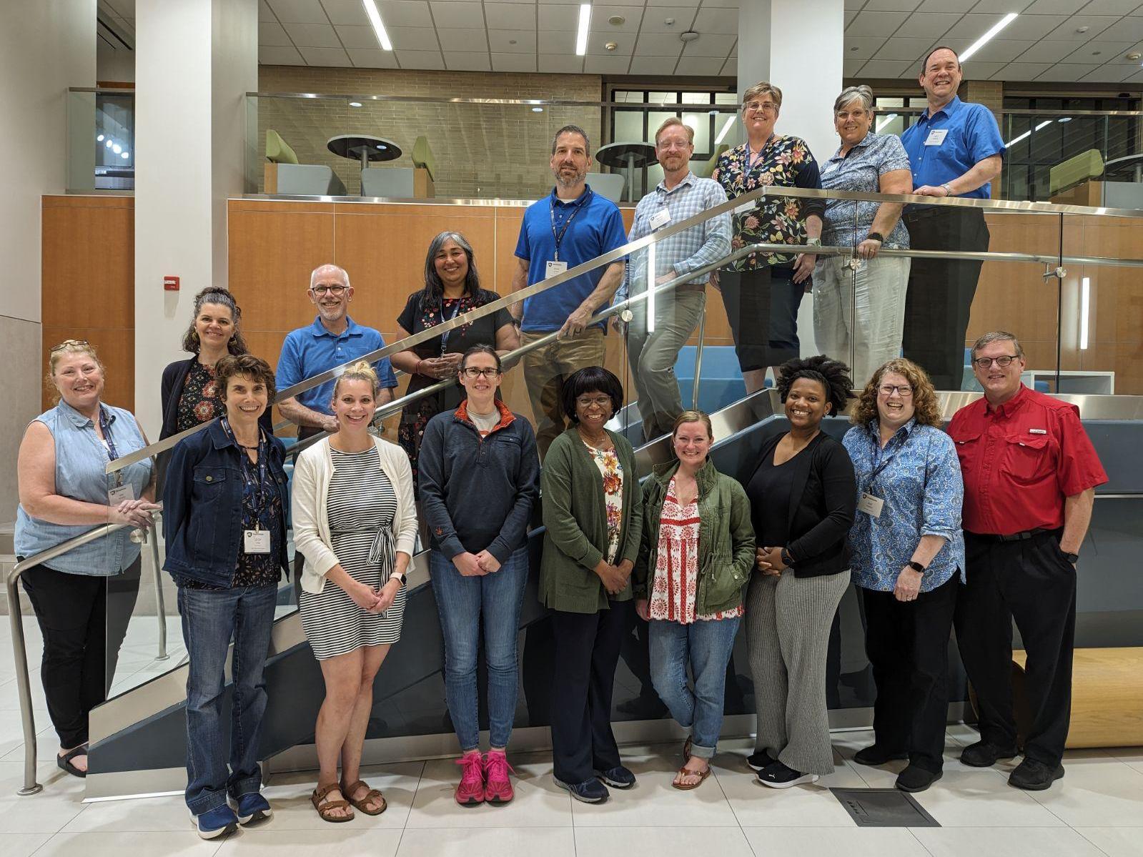 17 people pose for a group photo on and below a set of stairs