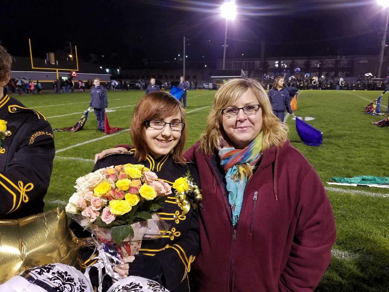 Marching band member and her mom on the sideline of a football game.