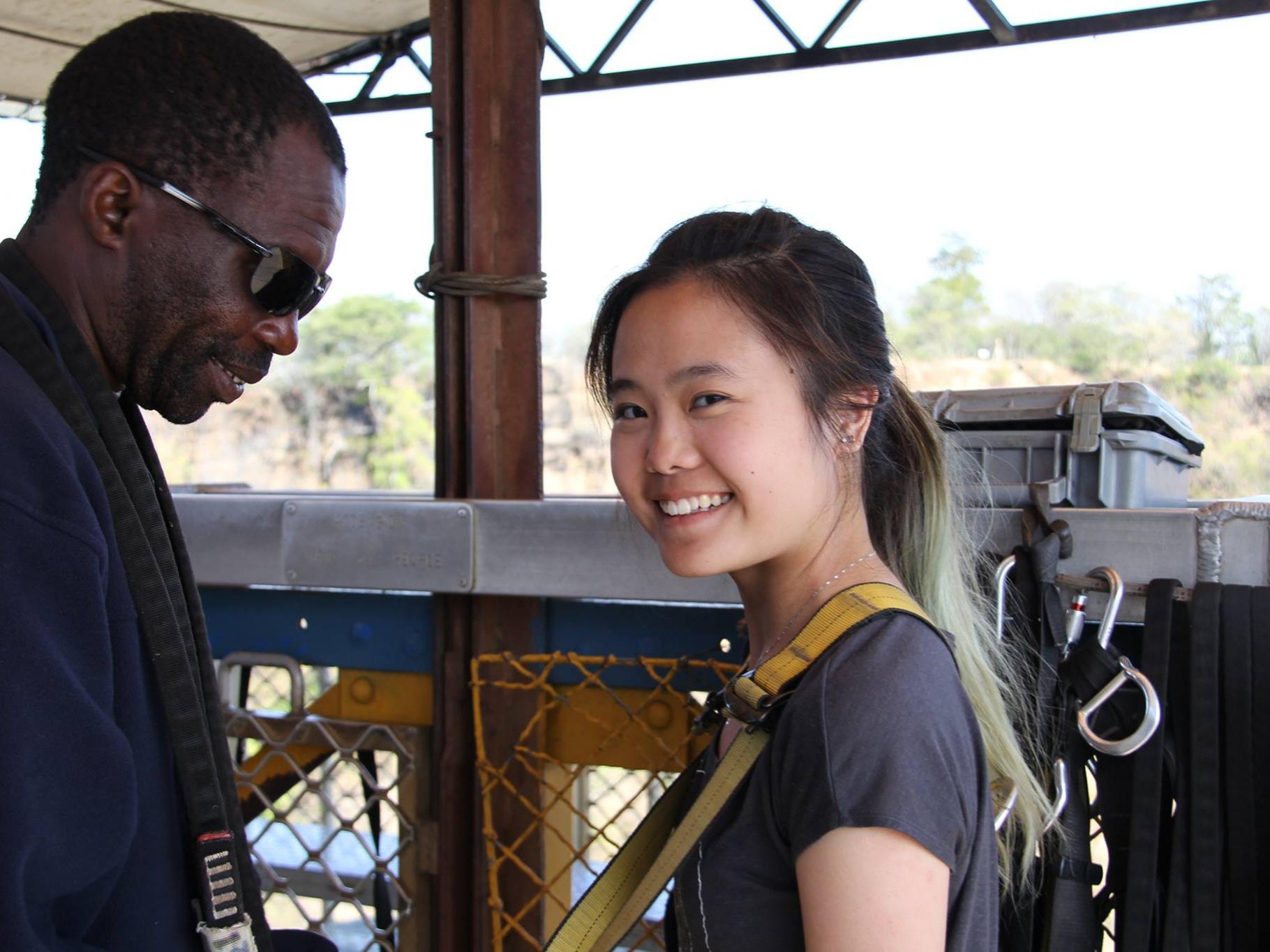 A woman and a man putting on jumping gear and smiling into the camera