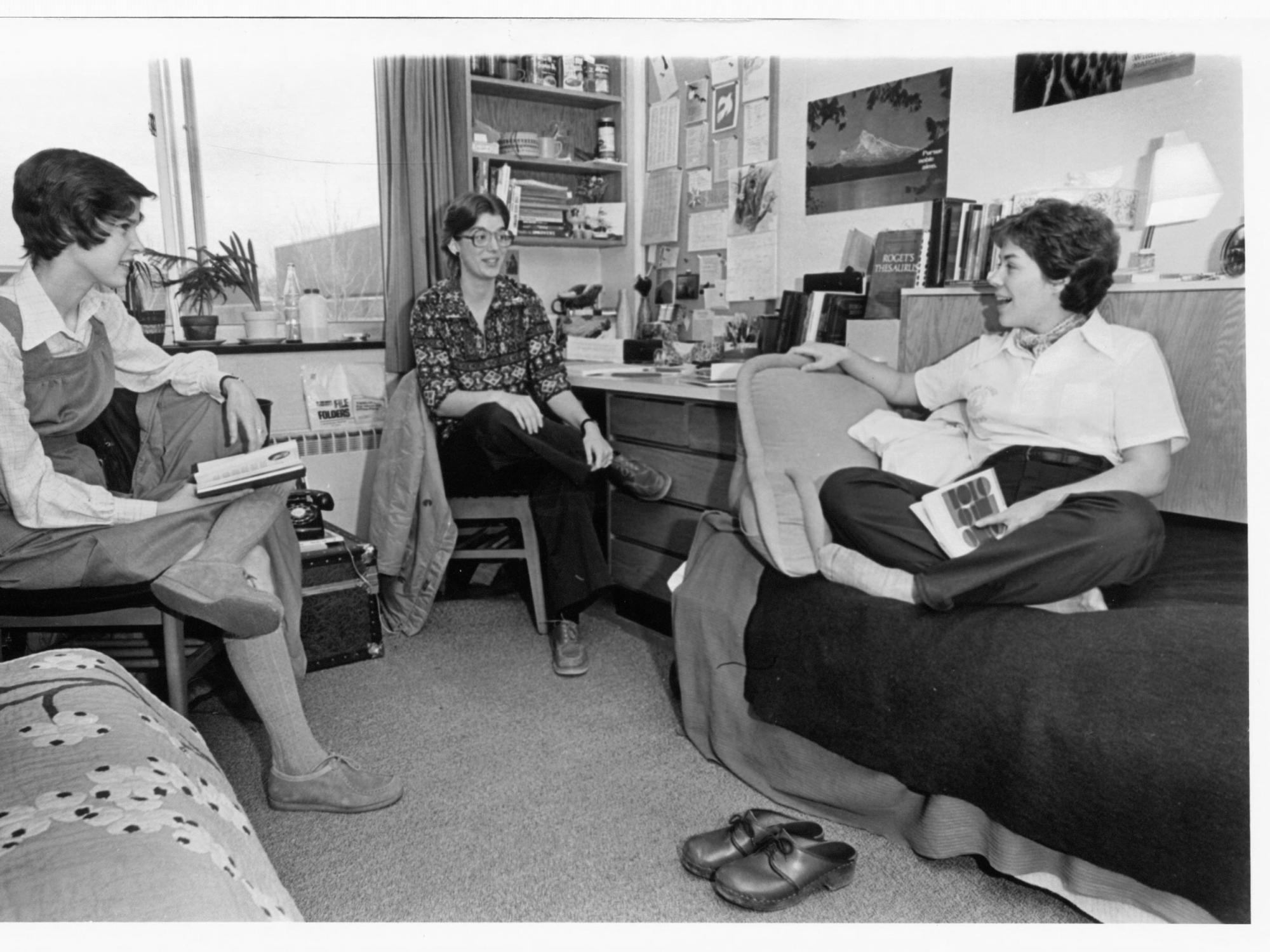 A black and white picture of three students in a dorm room