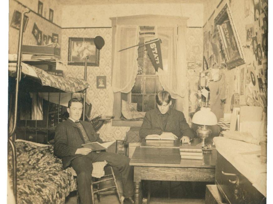 A black and white picture of two students in a dorm room in the 1900s