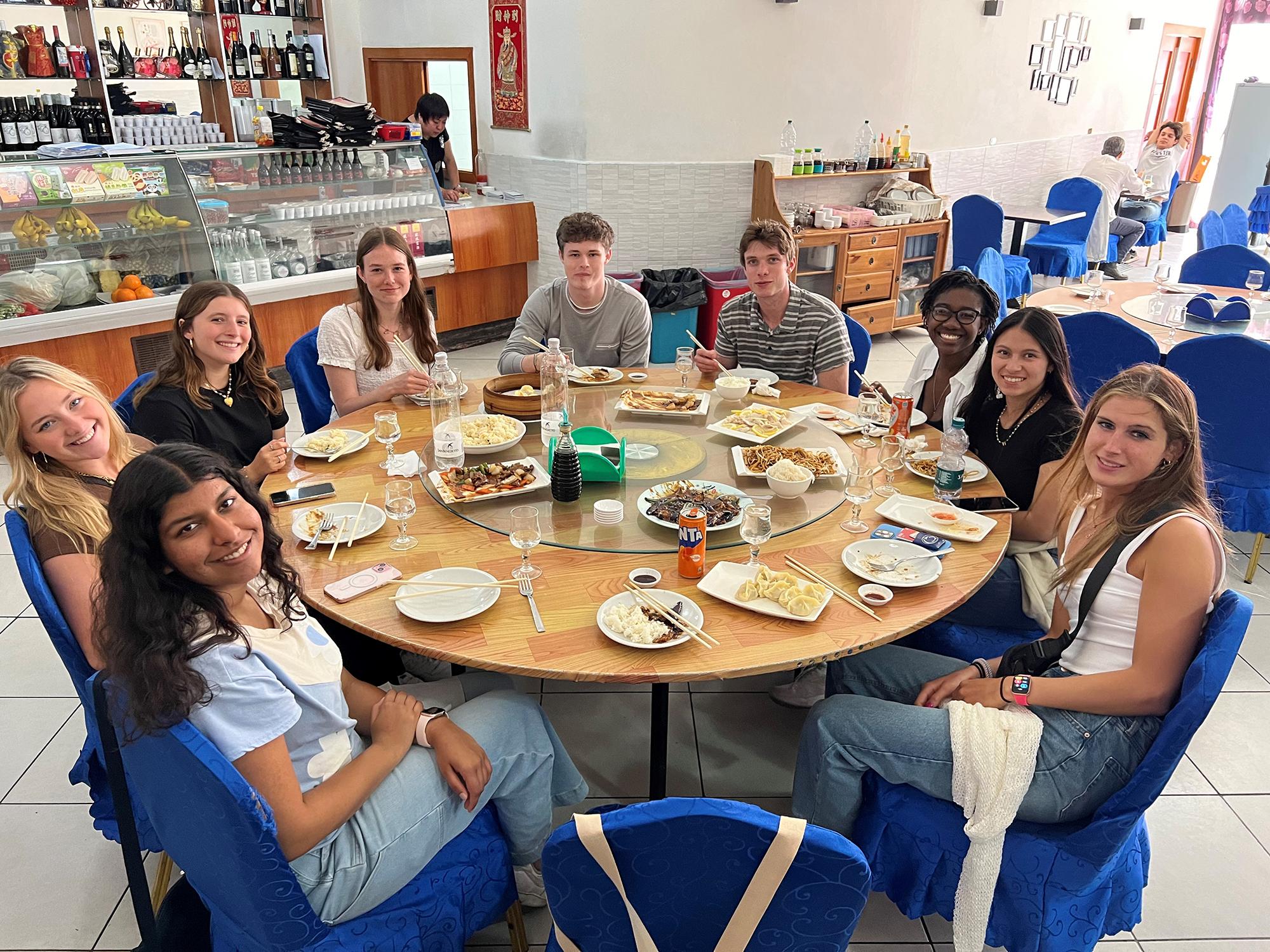 Students sit around a table full of authentic Chinese food.