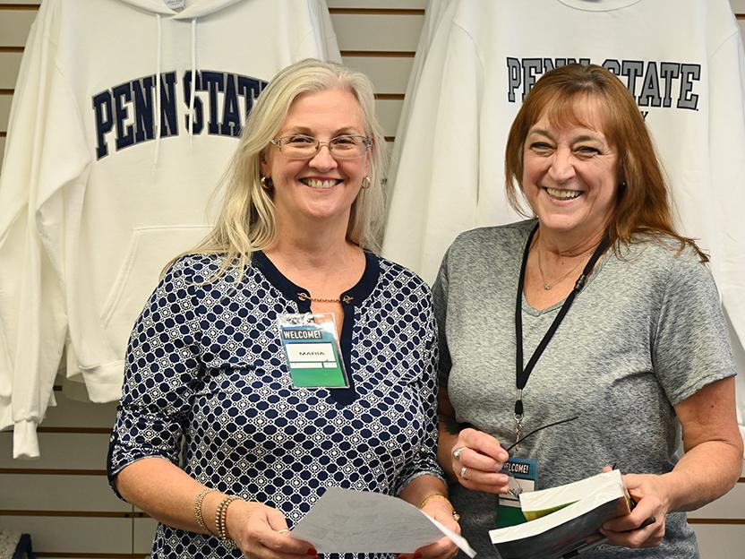 Two women standing next to each other in the campus bookstore, with Penn State gear on the wall behind them.