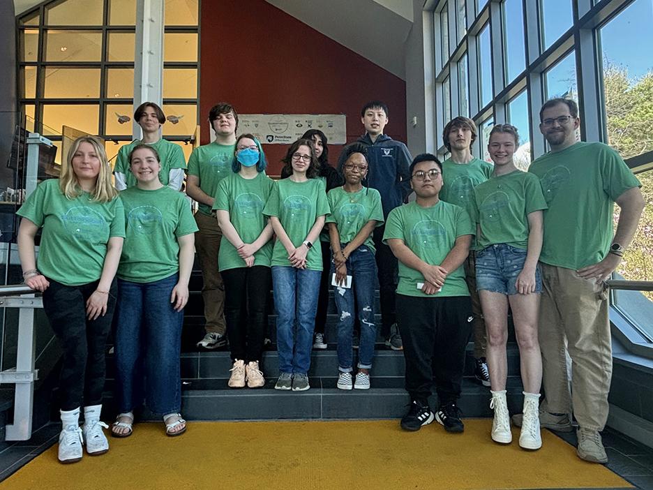 A group of students in matching green shirts promoting sustainability pose for a photo.