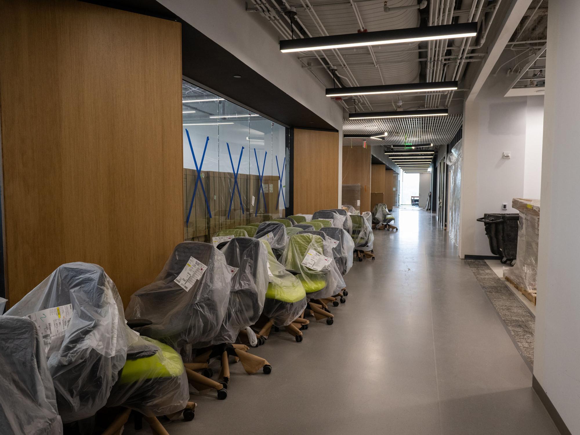  a line of chairs with plastic over them in a hallway