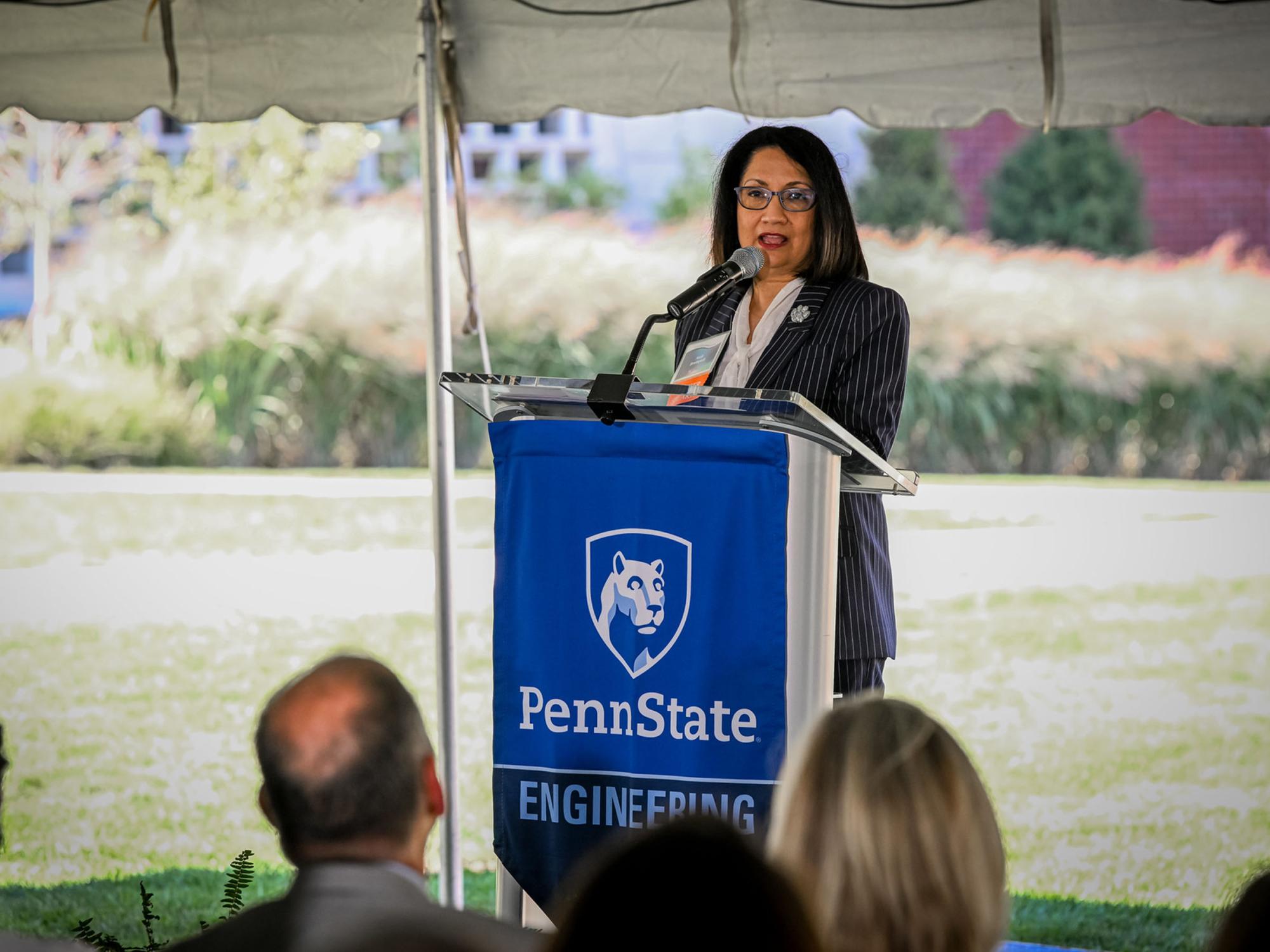 person speaks with microphone behind podium