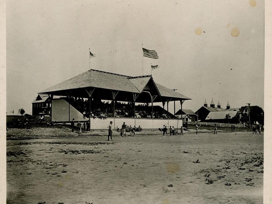 A grandstand with an American flag and two "PSC" flags at Old Beaver Field in the 1890s.