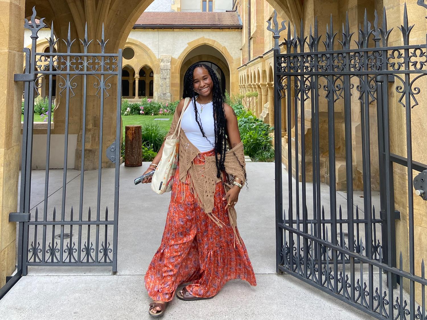 Rose Ried stands in a gated entryway in front of a courtyard in Neuchâtel, Switzerland.