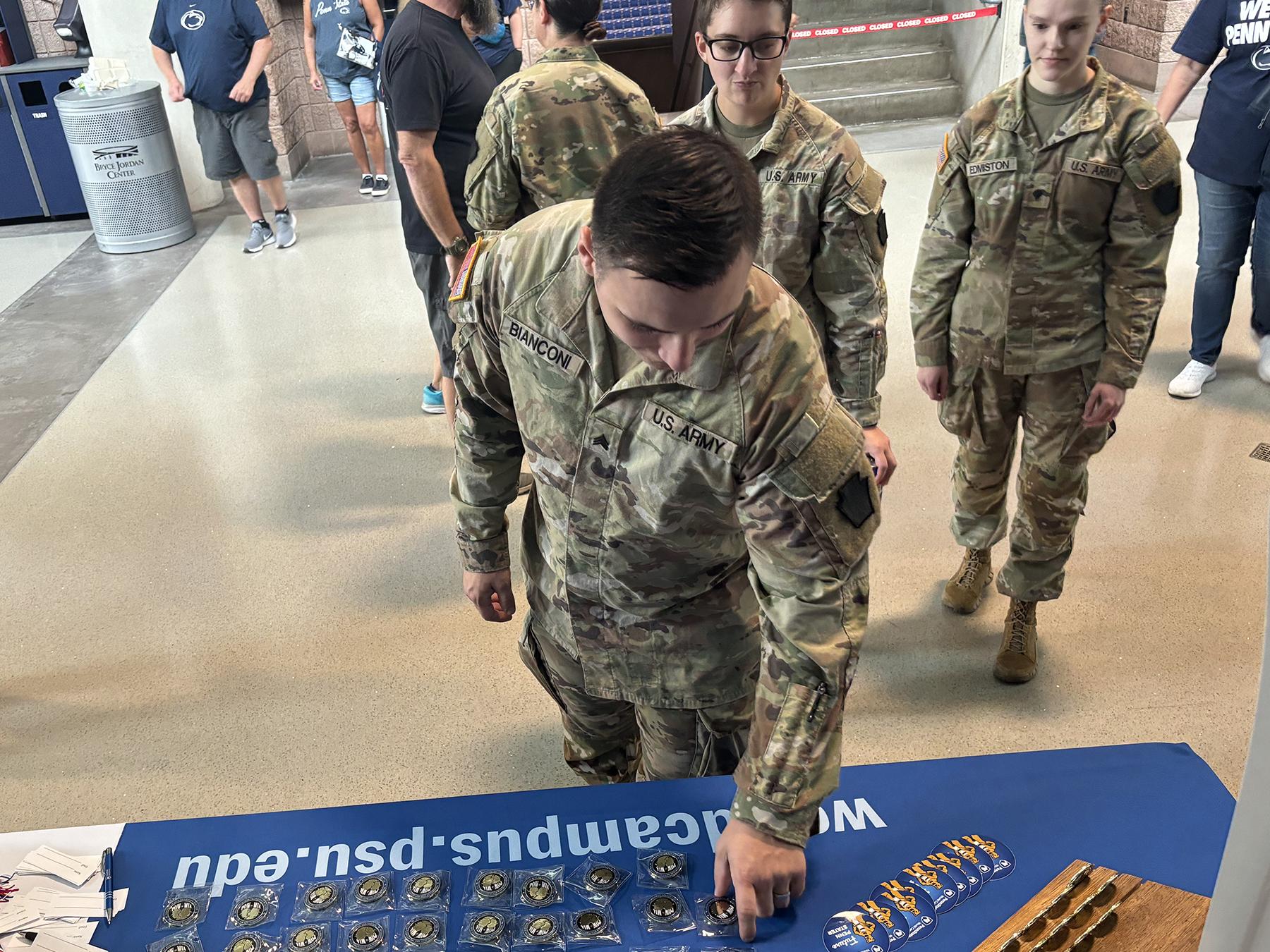 A man wearing a military uniform picks up a coin from a table.