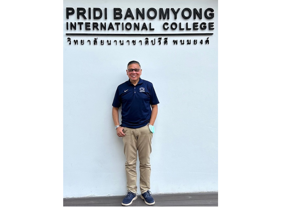 a man smiles in front of an international college 