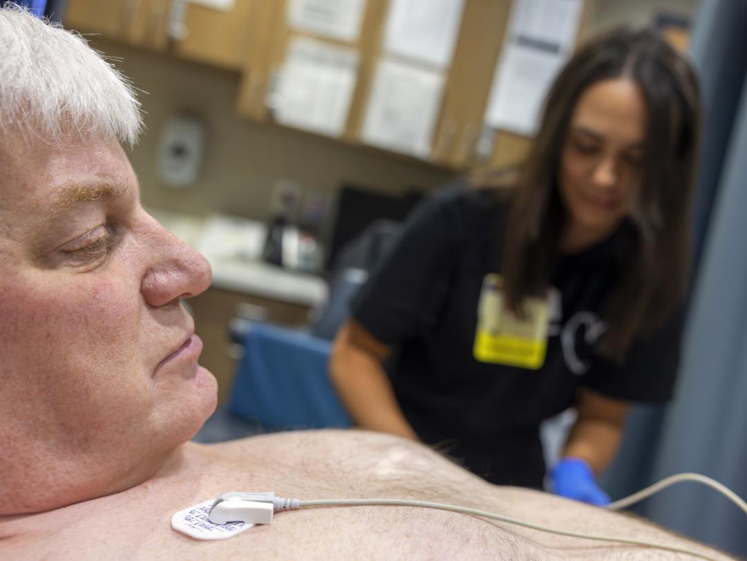 John Jones, left, looks at heart monitor leads as he gets a cardiac sonogram. Emily Kreider, is seen on the right, out of focus.