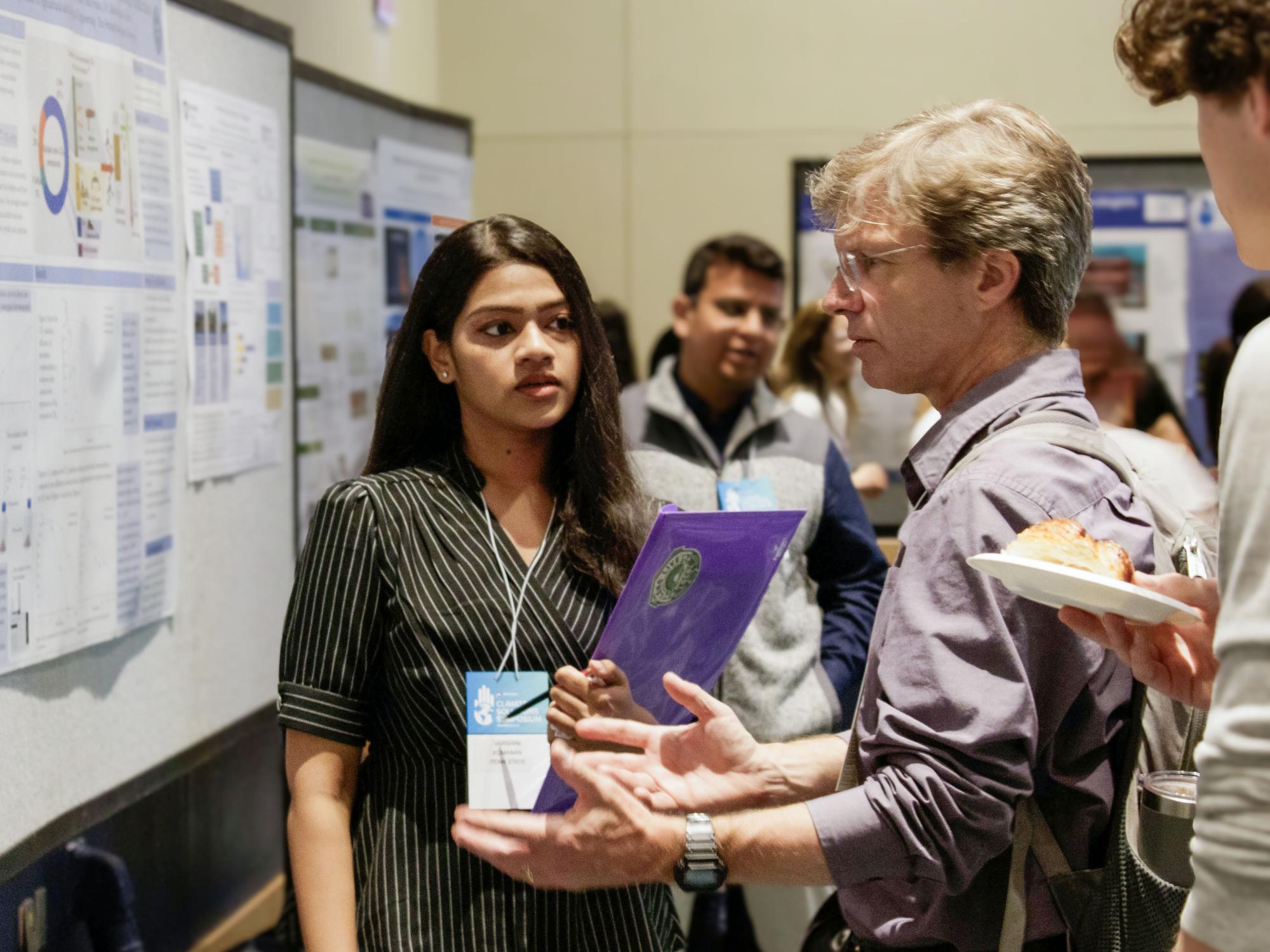 Ken Davis providing feedback to a student at a poster session.