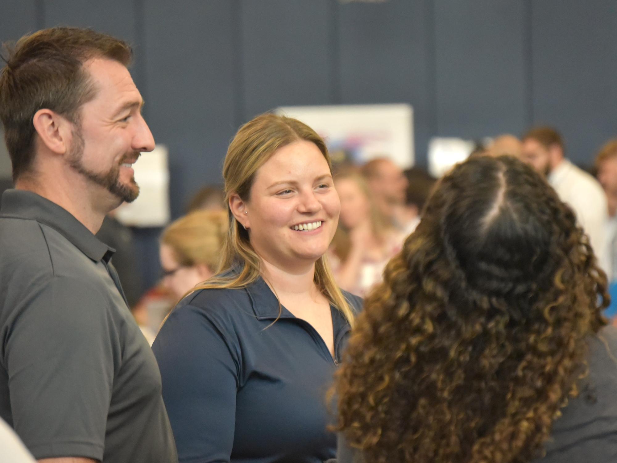 Two recruiters smile while talking with students at Penn State Behrend's career fair.