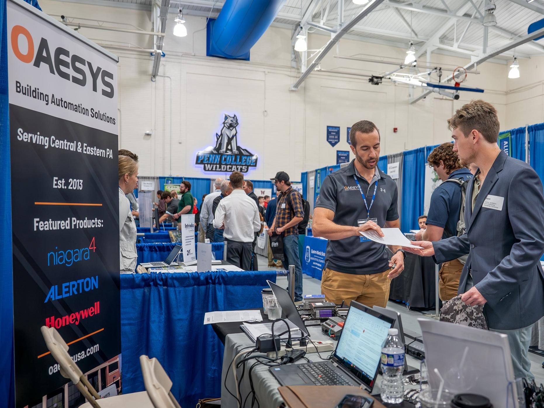 An employer and a student talk at a booth at the Penn College Career Fair. 