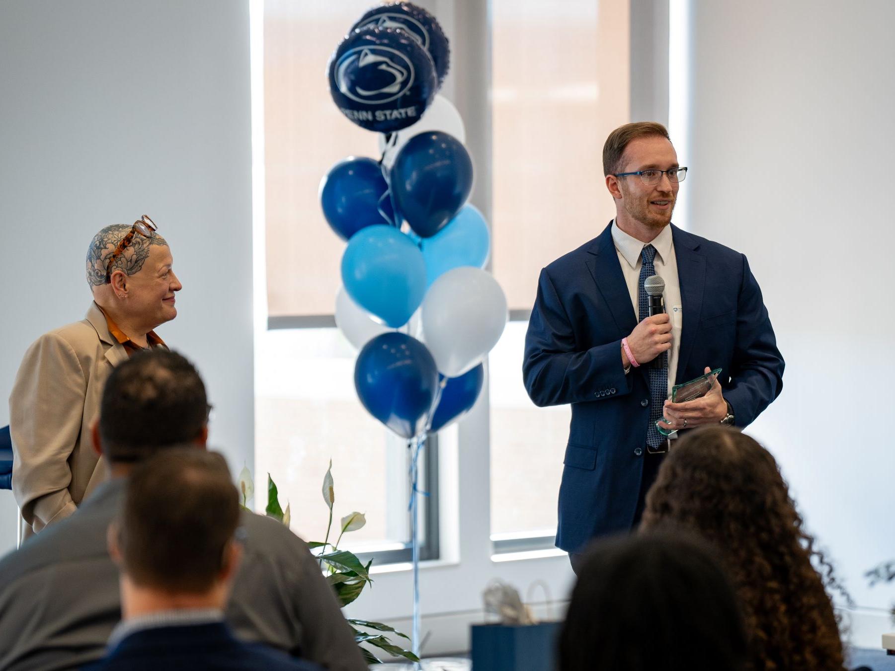 presenter and recipient at award ceremony with balloons in background